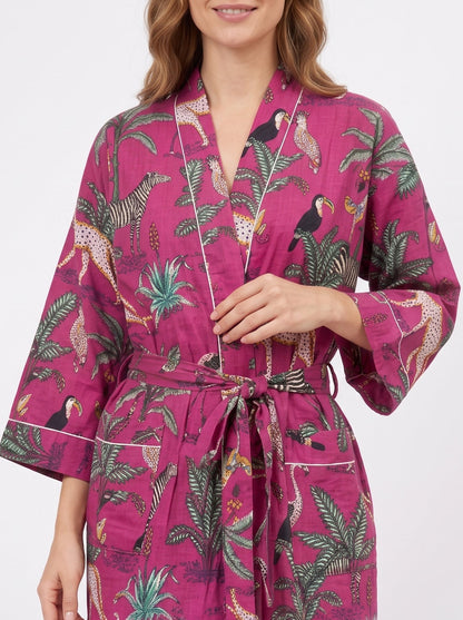 A woman wearing a magenta pink tropical print robe with a tie waist belt, shown against a plain white studio background.